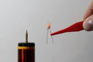 Picture of a neon glow lamp in a strong electromagnetic field. Please remark that the lamp held with insulating tweezers. (click to enlarge)